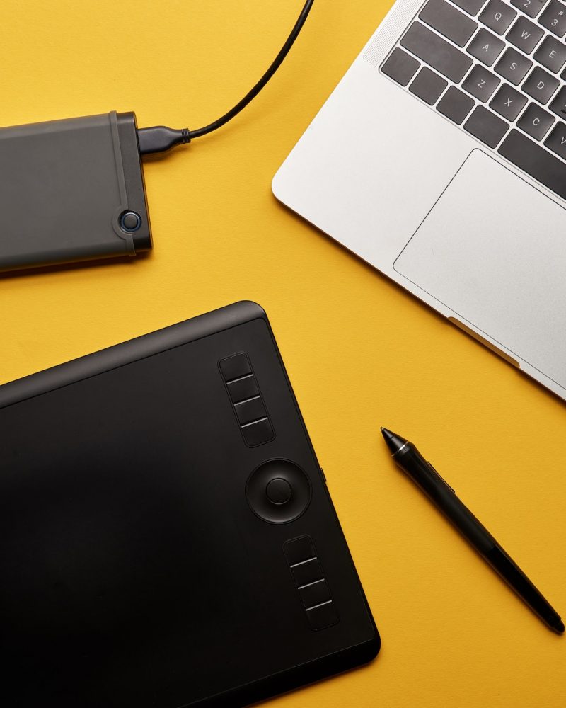 top view of various graphic designer gadgets on yellow surface